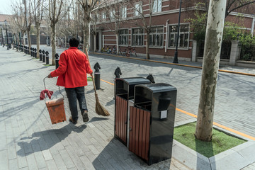 Lady in red jacket is cleaning the streets of the city. 