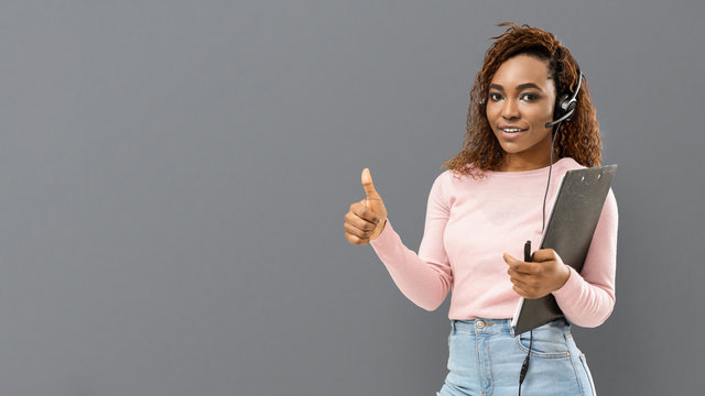 Young secretary girl with headset on showing thumb up