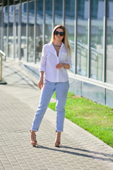 Street style fashion - lady in white shirt and boyfriend jeans walking along business centre