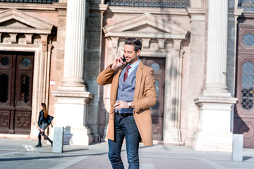 An elegant man standing on a square and talking on his phone