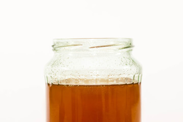 Jar filled with delicious bio honey close up shot on white background.