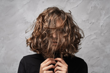 Closeup portrait of young lady with disheveled hair covering her face