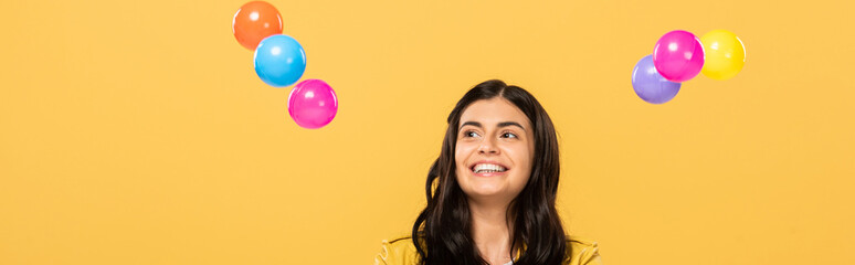 happy attractive girl with colorful balls, isolated on yellow