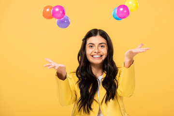 beautiful smiling girl with colorful balls, isolated on yellow