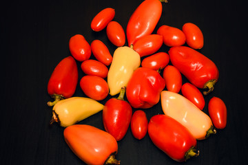 Tomatoes and peppers on dark wood