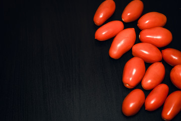 red ripe tomatoes in a row on a dark black background with copy space