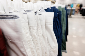Pants, shorts on hangers in the clothing store and textiles made of natural materials. The concept of seasonal sale