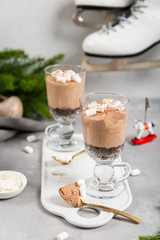 Homemade chocolate mousse dessert with marshmallows in glasses on grey background. Cheesecake in nice portion glasses. Winter dessert recipe. Close up