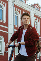 Young hipster in vintage hat smiling in front of old buildings