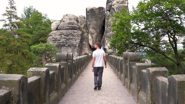 man walking over bastei bridge in saxony, germany