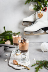 No-baked layered chocolate mousse and cheesecake with marshmallows in clear glasses on gray background. Recipe, creamy dessert, menu, cafe, copy space
