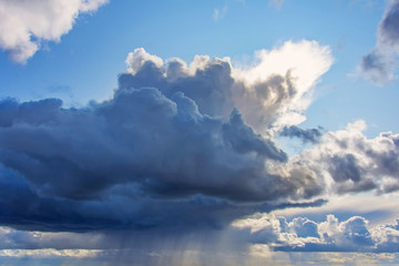 Obraz premium Powerful cumulonimbus dark cloud with heavy rain, tropical rain. Around the clear blue sky and the rising sun.