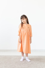 Childhood, kids and clothes designer concept - little girl posing in fashion clothes at studio