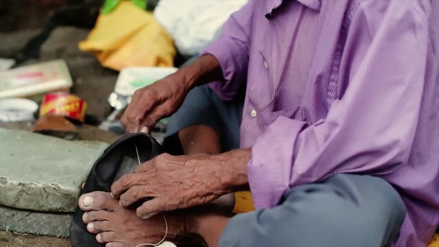 A cobbler repairing slippers of pilgrims by the roadside in the morning stock footage collection 1