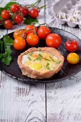 Baked rye tartlets with cheese and quail eggs on white wooden table