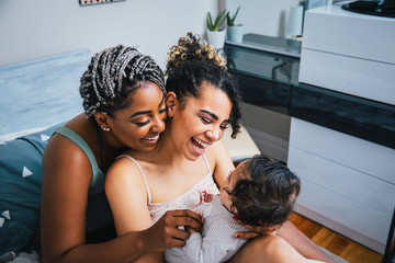 High angle view of cheerful lesbian mothers playing with adopted son in living room at home