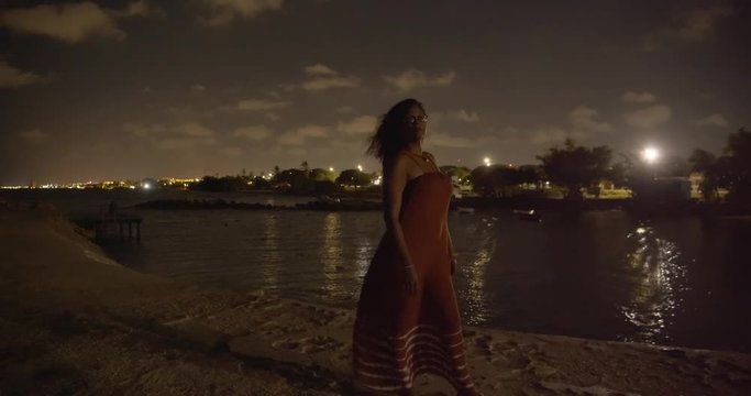 A model standing with her hair blowing in the wind at this amazing nightscape with city lights and stars in the background