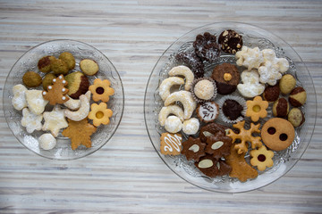 Many kinds of Christmas cookies on two cut glass transparent plates, sweet food on wooden table