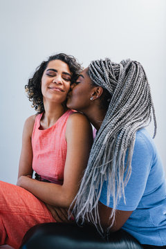 Lesbian woman kissing girlfriend while sitting at home
