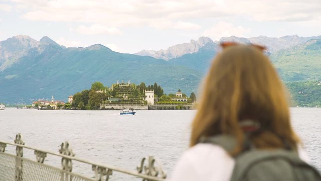Woman walking and looking at isola bella in lago maggiore, Italy.