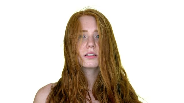 Close-up of a beautiful red-haired woman which is posing in front of the camera with a white screen in the background.