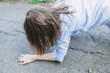 Young woman with heart problems lying on street facing down