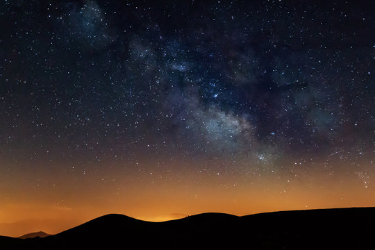 Photograph of the night sky in the mountains, with a view of the Milky Way. Visible stars during sunset. Galaxy, universe.