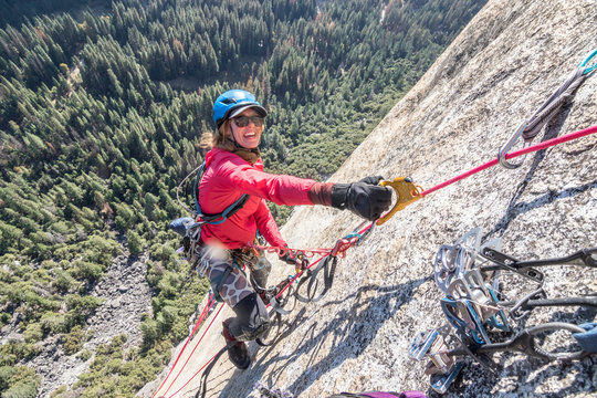 A young woman is all smiles while jumaring on a fixed rope way high up