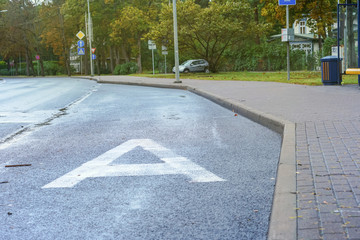 capital letter A is painted in white on asphalt road at bus stop on city street
