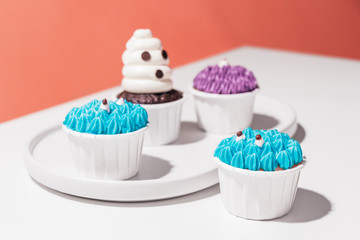 Halloween cupcakes on white and pink background, creative minimal Halloween party concept with copy space