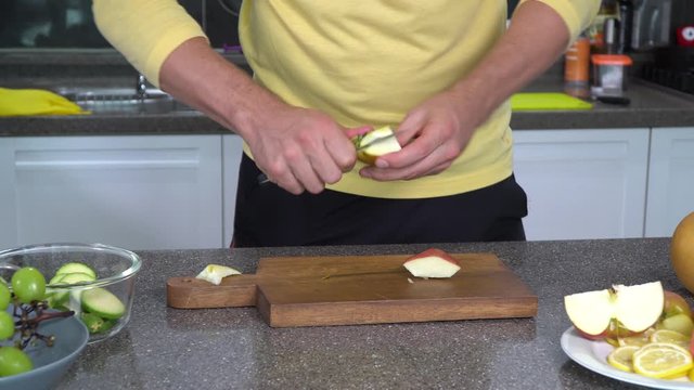 Model Wearing A Yellow Shirt Is Carefully Cutting A Large Apple On A Wooden Board In A Modern Kitchen