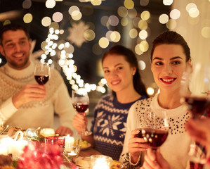 winter holidays and people concept - happy friends celebrating christmas at home and drinking red wine