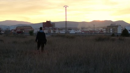 Young man is walking on a meadow out of town