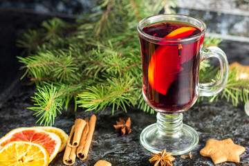 Fototapeta na wymiar Christmas mulled wine with ginger biscuits orange cinnamon clove anise and fir tree on the dark table