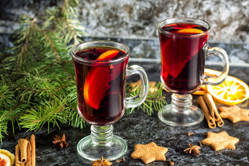 Christmas mulled wine with ginger biscuits orange cinnamon clove anise and fir tree on the dark table