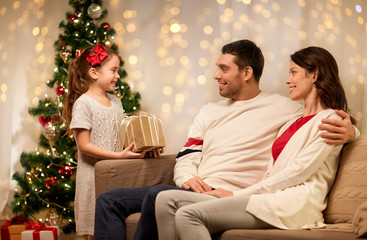 holidays, family and celebration concept - happy mother, father and little daughter with christmas present at home