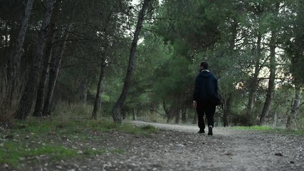 Young man is walking with his backpack in a forest