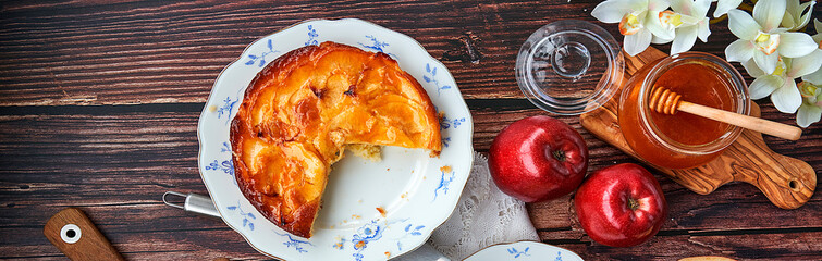 Homemade apple pie bathed with peach jam and honey. White flowers, jar of peach jam and honey....