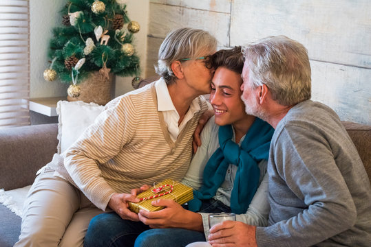 Christmas Gifts Moment At Home With  Parents And Grandfathers And Young Son Or Grandson - Love Moment And Traditioal Celebration For People Family Together - Christmas Tree In Background