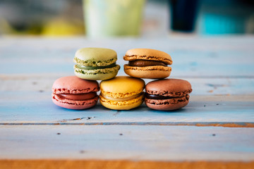 Close up of tasty bakery macarones on a blue woden rustic table - sweet cakes made from bakery chef with cream and chocolate flavours