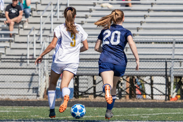 Fototapeta premium Two girls chasing soccer ball