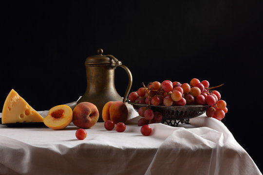 A vase of grapes, peaches, cheese and an old pitcher