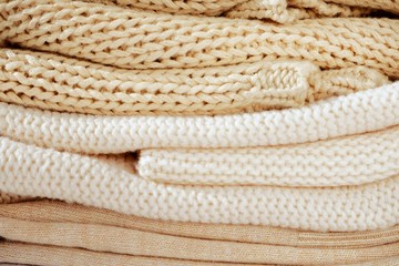 Fototapeta na wymiar Close-up of knitted clothes in warm beige shades with a different pattern of the fall / winter season texture, background. With selective focus, copy space for text.