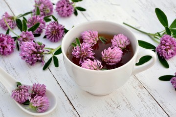 Clover flowers  and clover drink in сup on white wooden background