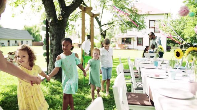 Kids on birthday party playing outdoors in garden in summer, celebration concept.