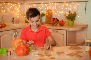 teen boy cooking cookies at home in the kitchen for halloween