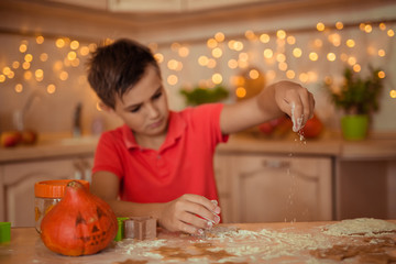 teen boy cooking cookies at home in the kitchen for halloween