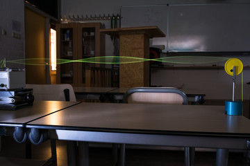 Demonstration of standing waves on a string, illuminated by stroboscope. Physics experiment.