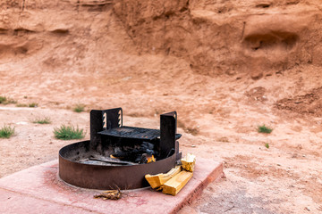 Campfire fire pit grill by logs and desert landscape with nobody in Goblin Valley State Park campground camp site