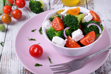 Light salad with broccoli, cherry tomatoes and feta cheese in a white ceramic bowl